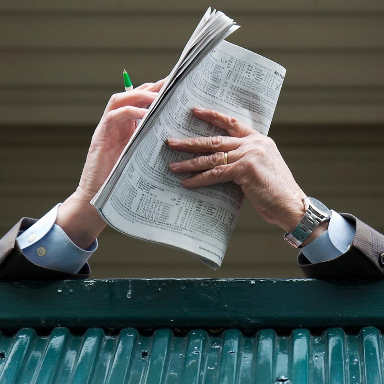 close up view of man holding a racing program